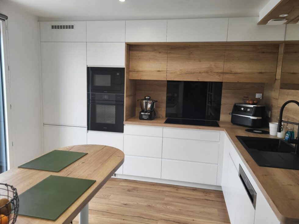 Cuisine blanche avec colonnes électroménager noires et bar en chêne